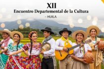 Artistas huilenses celebran el XII Encuentro Departamental de la Cultura con trajes típicos, instrumentos y artesanías en un paisaje montañoso con arrozales y un puente.