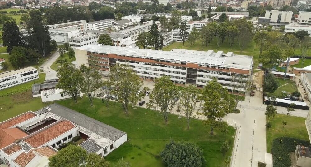 Vista aérea de varios edificios universitarios rodeados de zonas verdes en el campus de la Universidad Nacional de Colombia en Bogotá.
